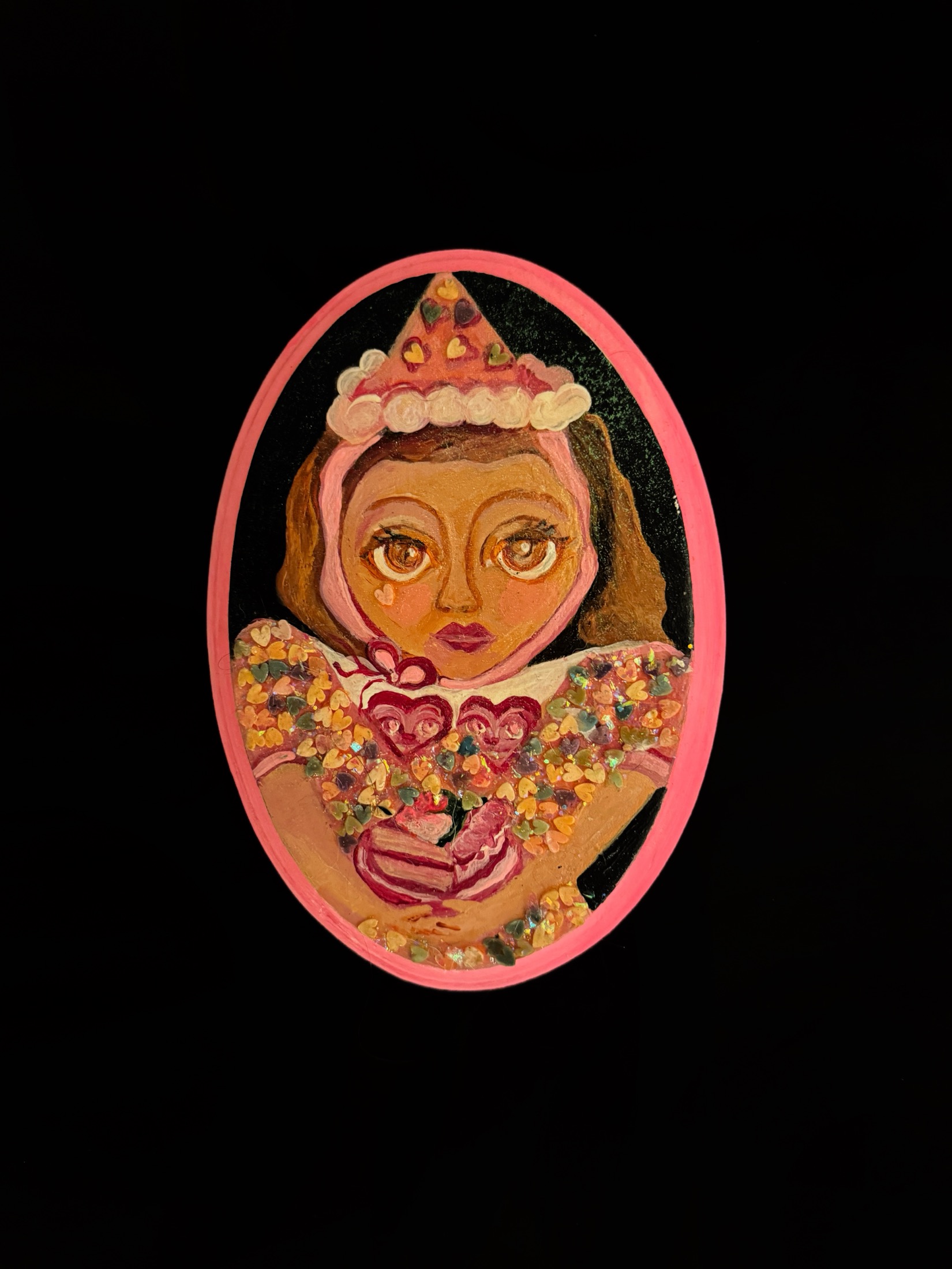 A girl in a party hat holding a pink cake, on an oval panel with a pink border